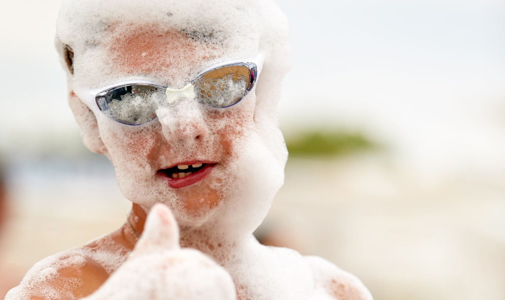 bambino che si diverte allo schiuma party in spiaggia